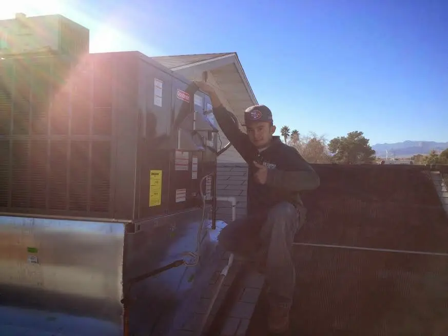 HVAC technician performing AC Tune-Up on a rooftop unit in Neptune